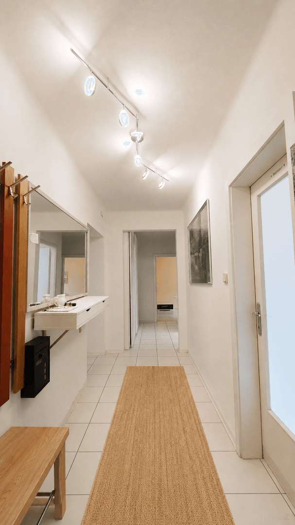 Heller Flur mit Fliesenboden, Garderobe und Spiegel, einladend gestaltet und praktisch ausgestattet.