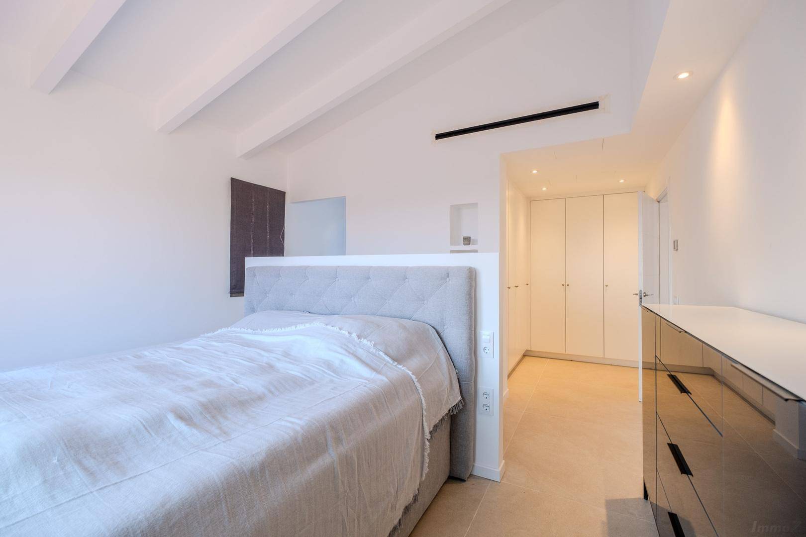 Modernes Schlafzimmer mit Doppelbett, Einbauschränken und indirekter Beleuchtung.