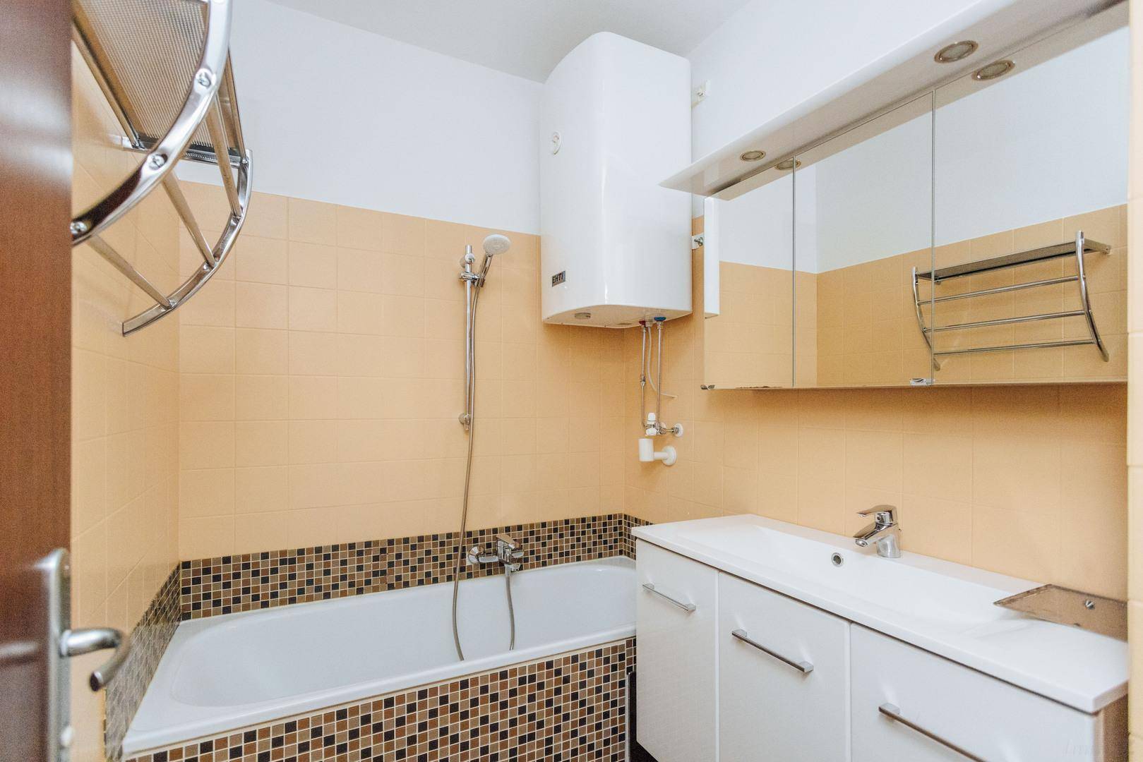 Funktionelles Badezimmer mit Badewanne, Waschtisch und Spiegelschrank.