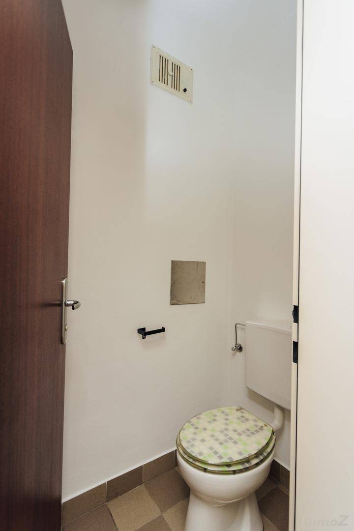 Separates WC mit Toilette und Lüftungsgitter, einfach und funktional.