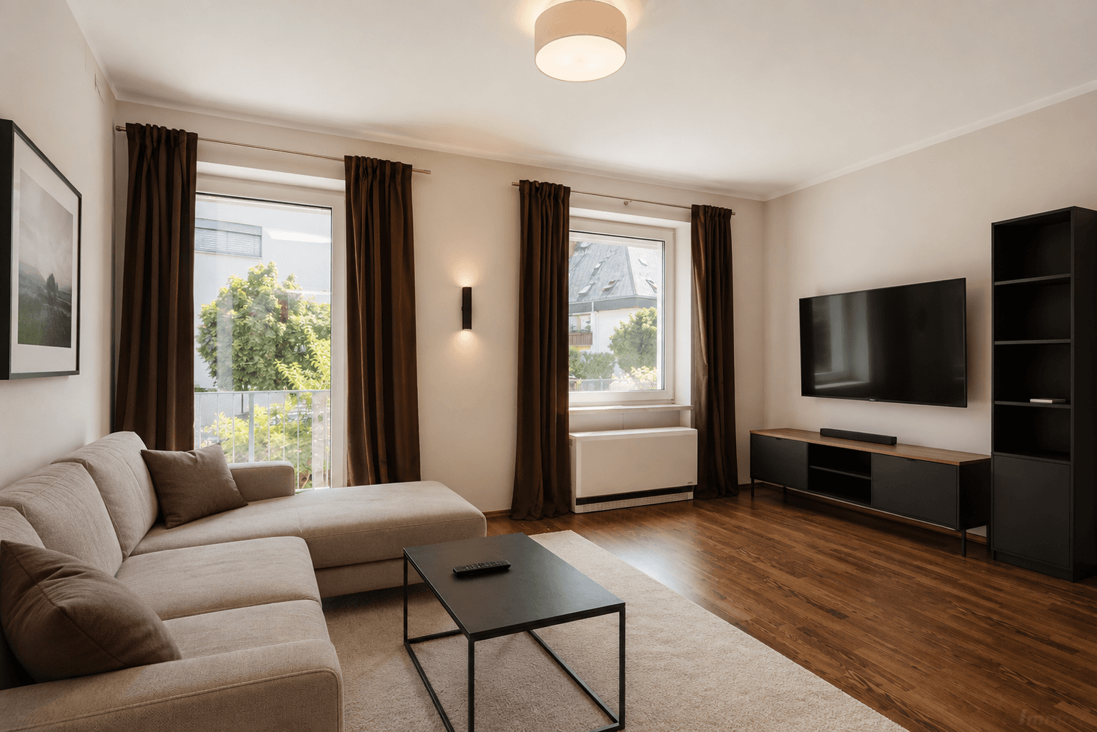 Geräumiges Wohnzimmer mit Holzboden, großem Sofa und Zugang zum Balkon.