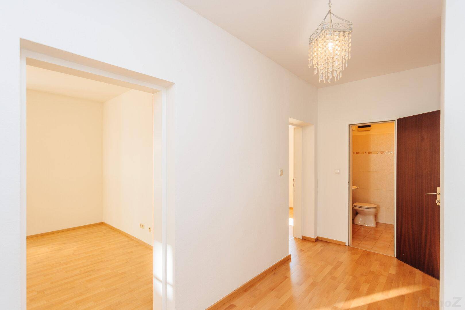 Geräumiger Flur mit Holzboden, der zu einem leeren Zimmer und einem Badezimmer führt.