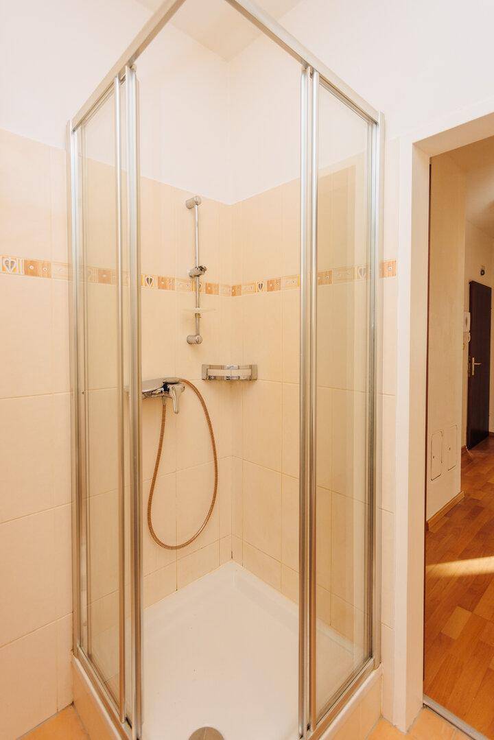 Duschkabine mit Glaswänden und beigefarbenen Fliesen in einem gepflegten Badezimmer.