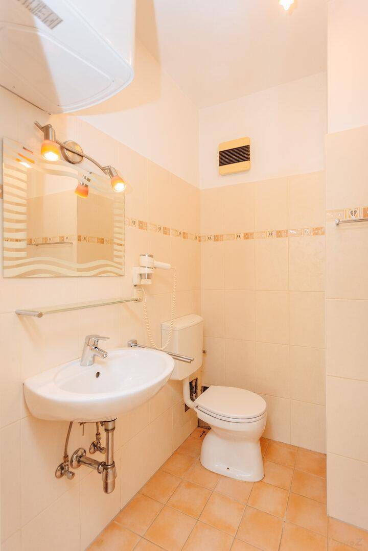Helles Badezimmer mit Waschbecken, Toilette und beigefarbenen Fliesen, gut gepflegt.