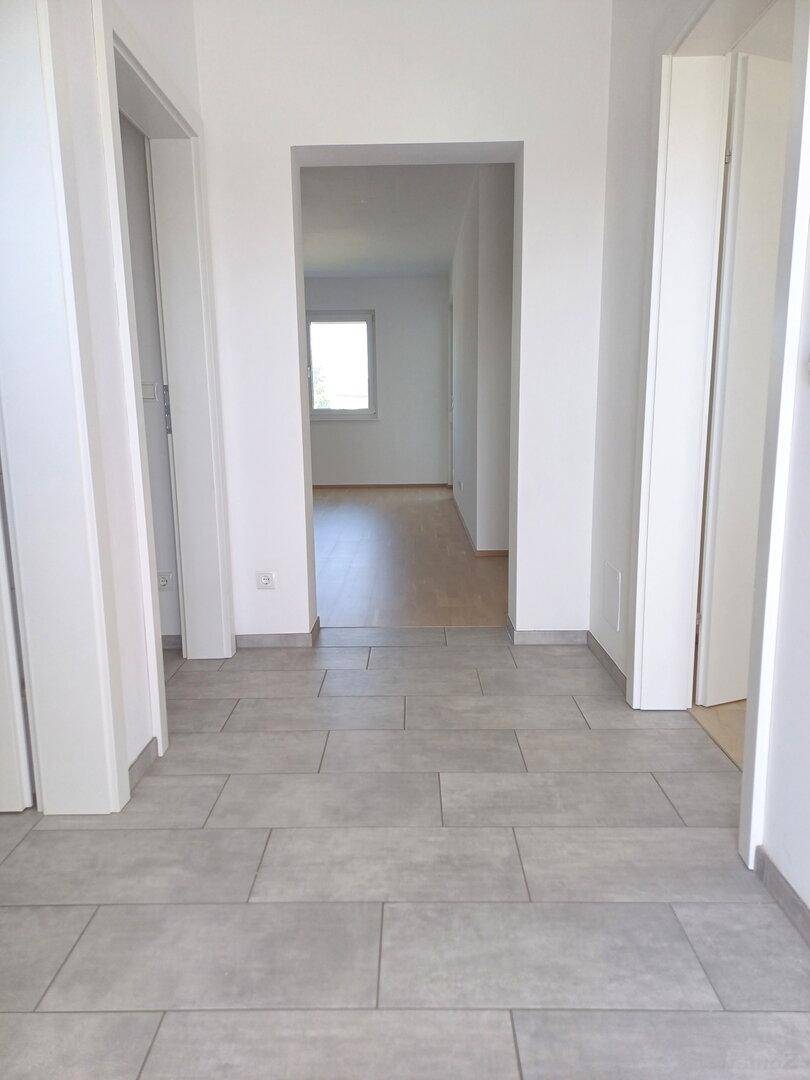 Heller Flur mit modernen grauen Fliesen, der zu weiteren Räumen der Wohnung führt und einladend wirkt.