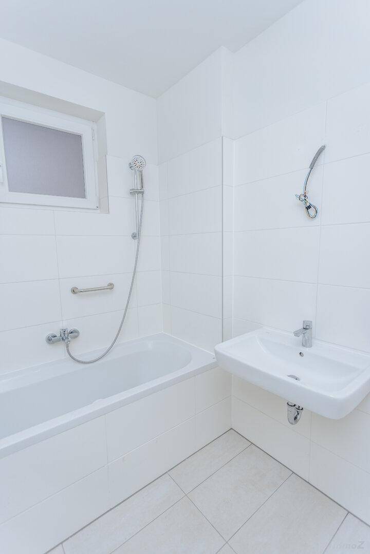 Helles Badezimmer mit Badewanne, Dusche und Waschbecken.