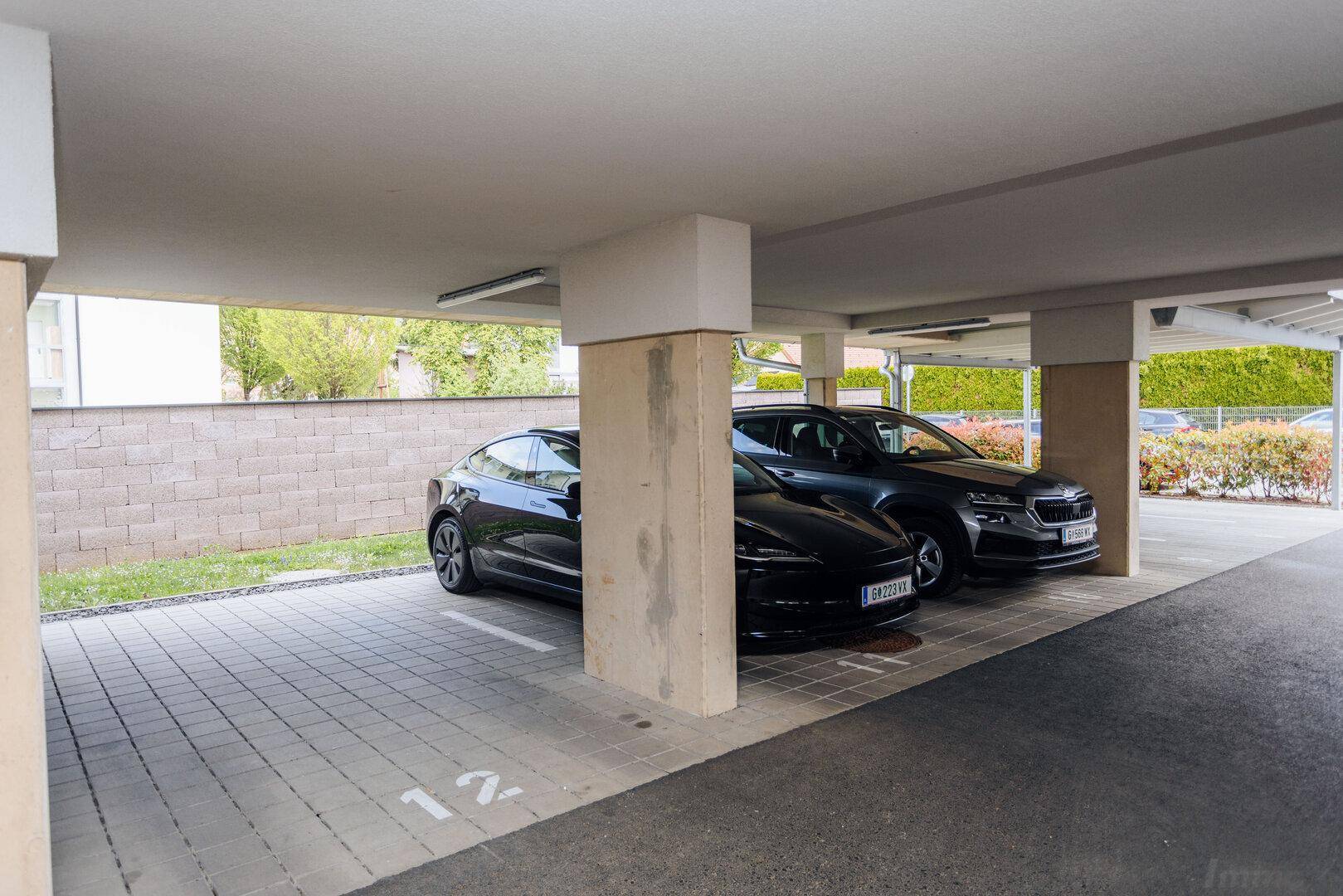 Überdachte Parkplätze für Fahrzeuge unter dem Gebäude.