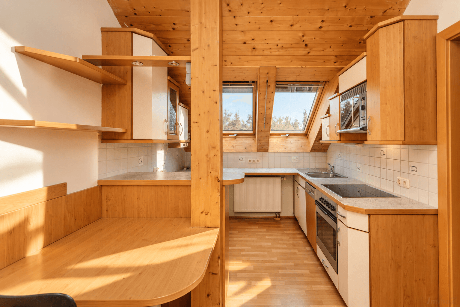 Geräumige Holzküche im Dachgeschoss mit viel Stauraum und natürlichem Lichteinfall durch Dachfenster.