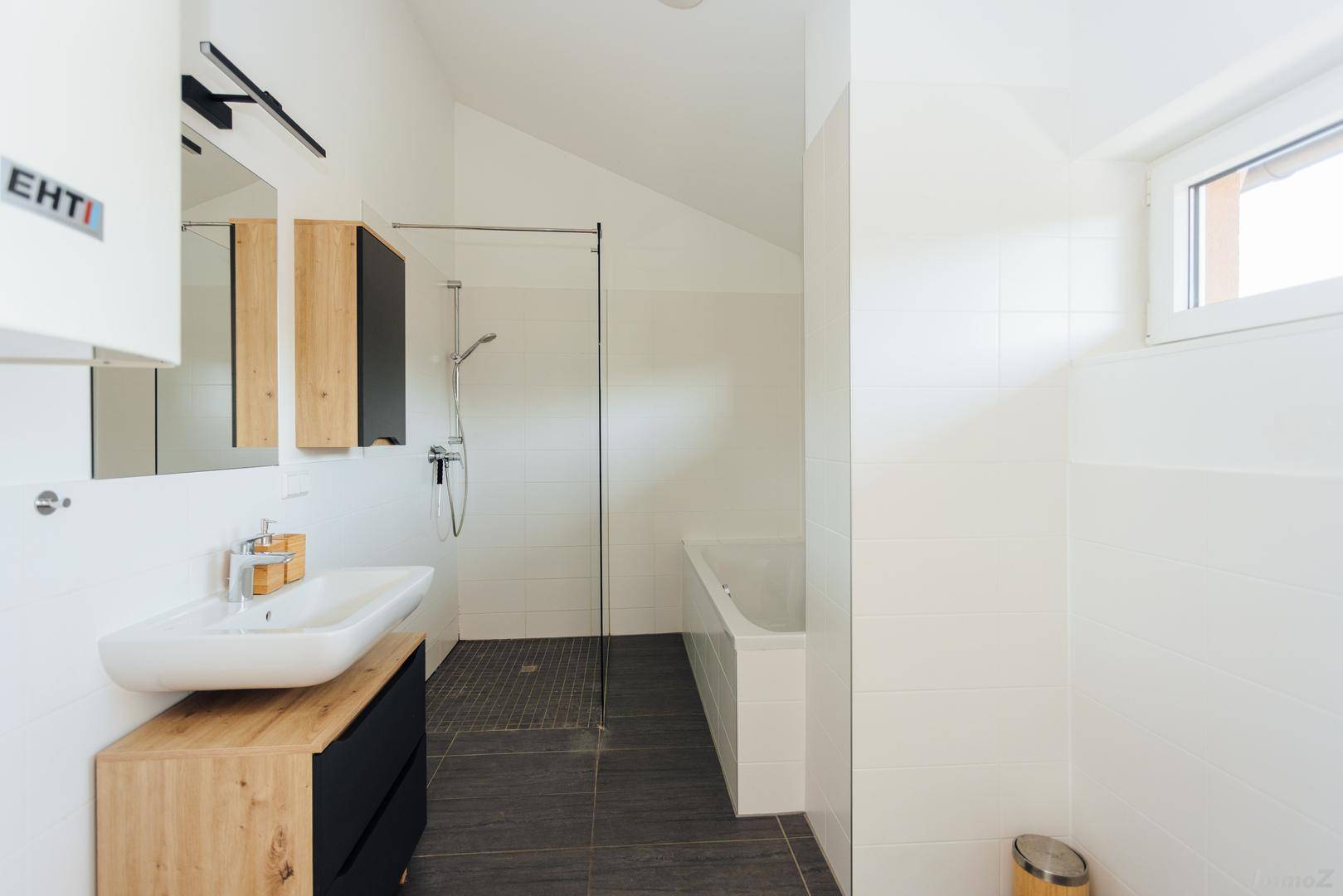 Helles Badezimmer mit Badewanne, Dusche und modernem Waschtisch.