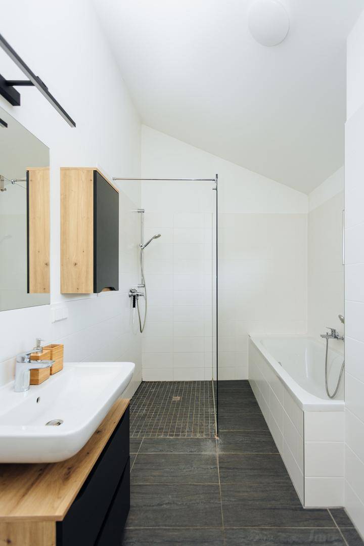 Modernes Badezimmer mit Badewanne, Dusche und Waschtisch, gut beleuchtet.