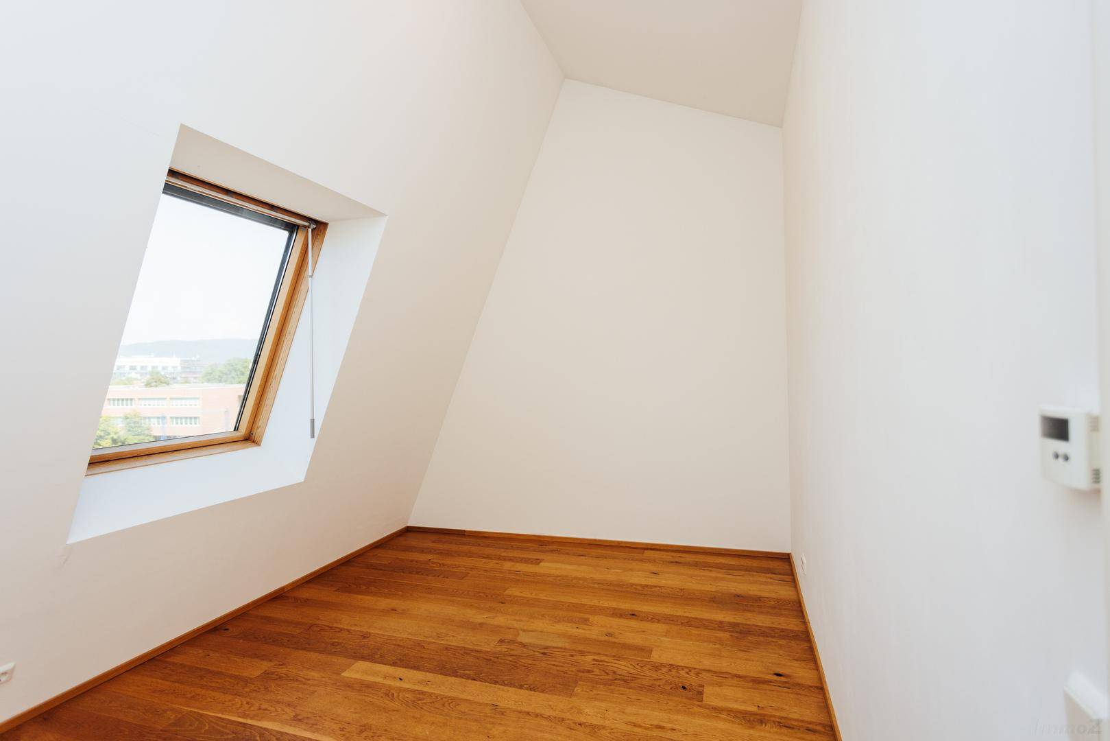 Helles Zimmer im Dachgeschoss mit Holzboden und schrägem Dachfenster, ideal als Schlafzimmer.