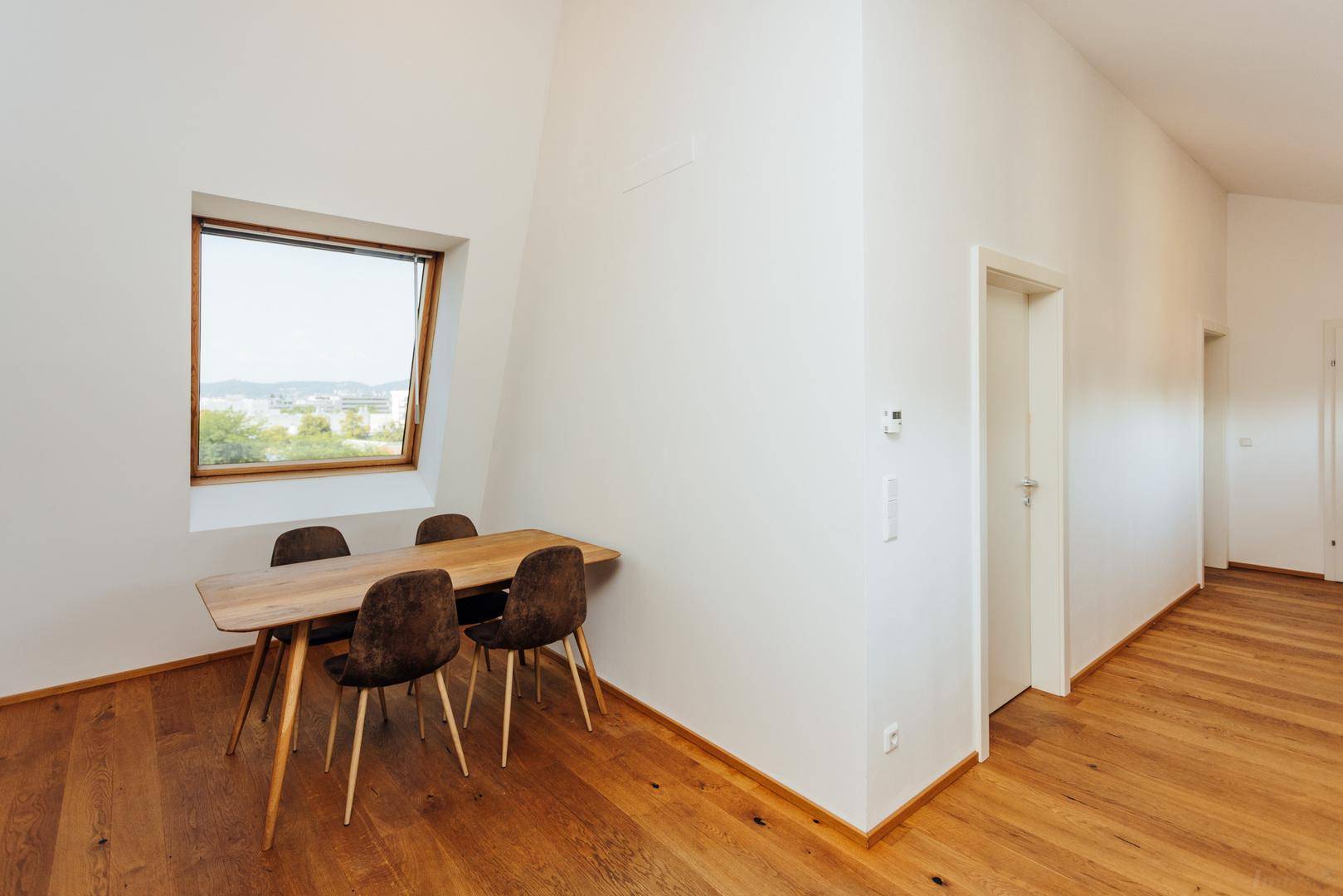 Essbereich mit Holztisch, Dachfenster und Zugang zu weiteren Räumen.