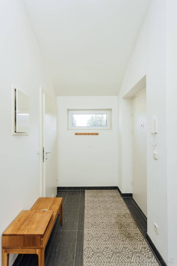 Langer Flur mit Sitzbank, Garderobe und einer Kombination aus Fliesen- und Teppichboden.