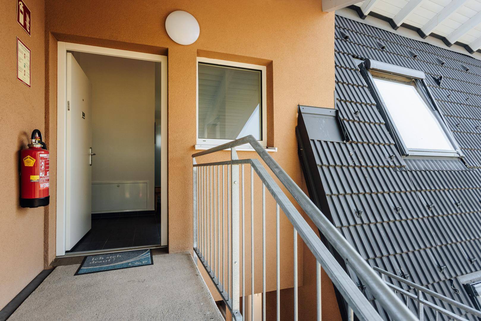 Eingangsbereich des Gebäudes mit Treppe und Blick auf das Dach mit Dachfenstern.