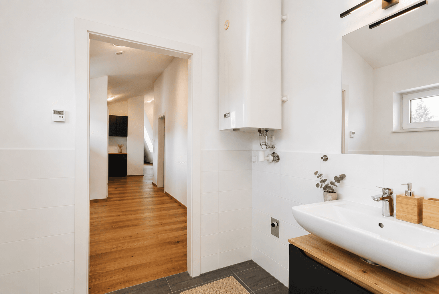 Modernes Badezimmer mit Waschbecken, Boiler und Blick in den Flur.