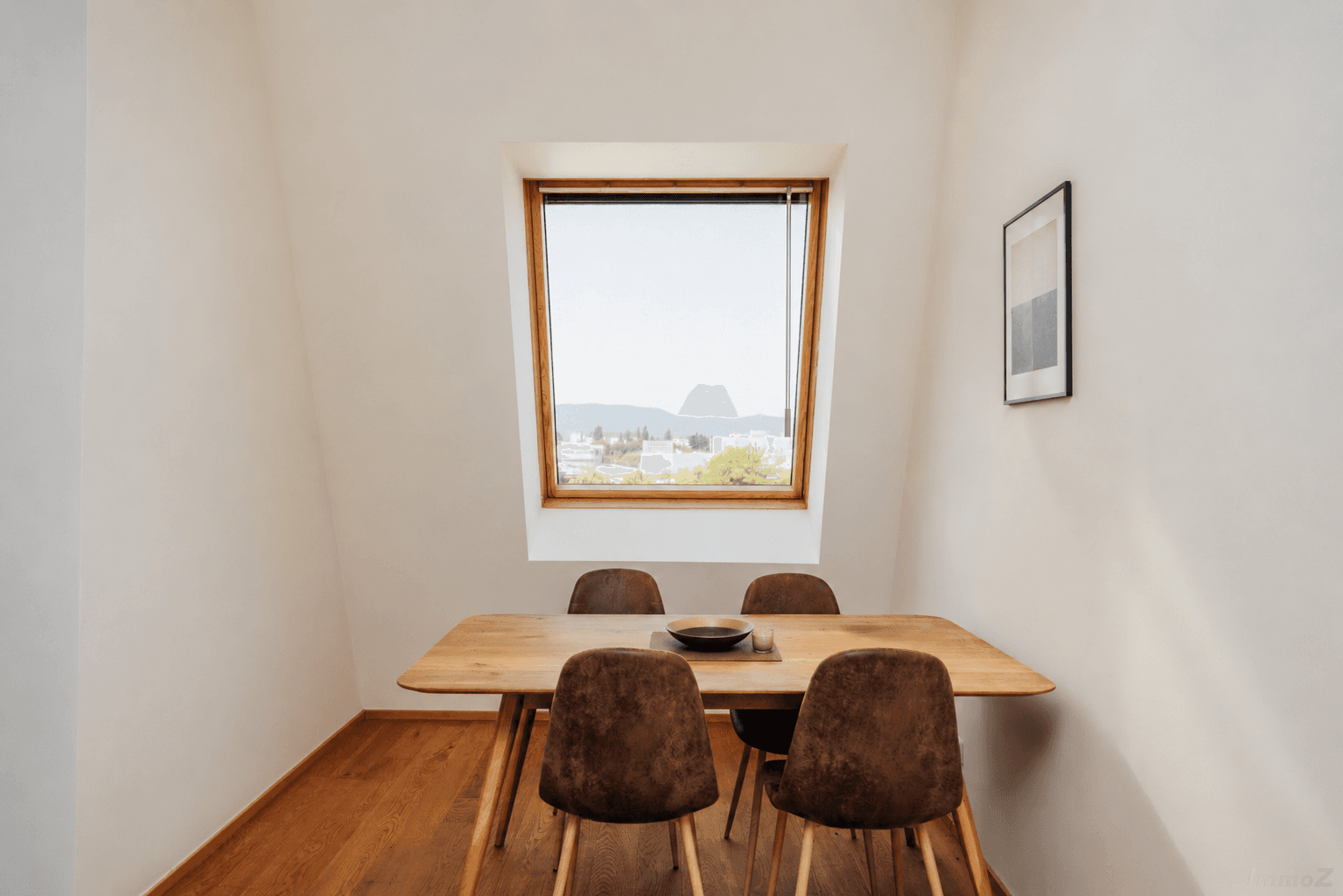 Gemütlicher Essbereich mit Holztisch, modernen Stühlen und einem Dachfenster mit Bergblick.
