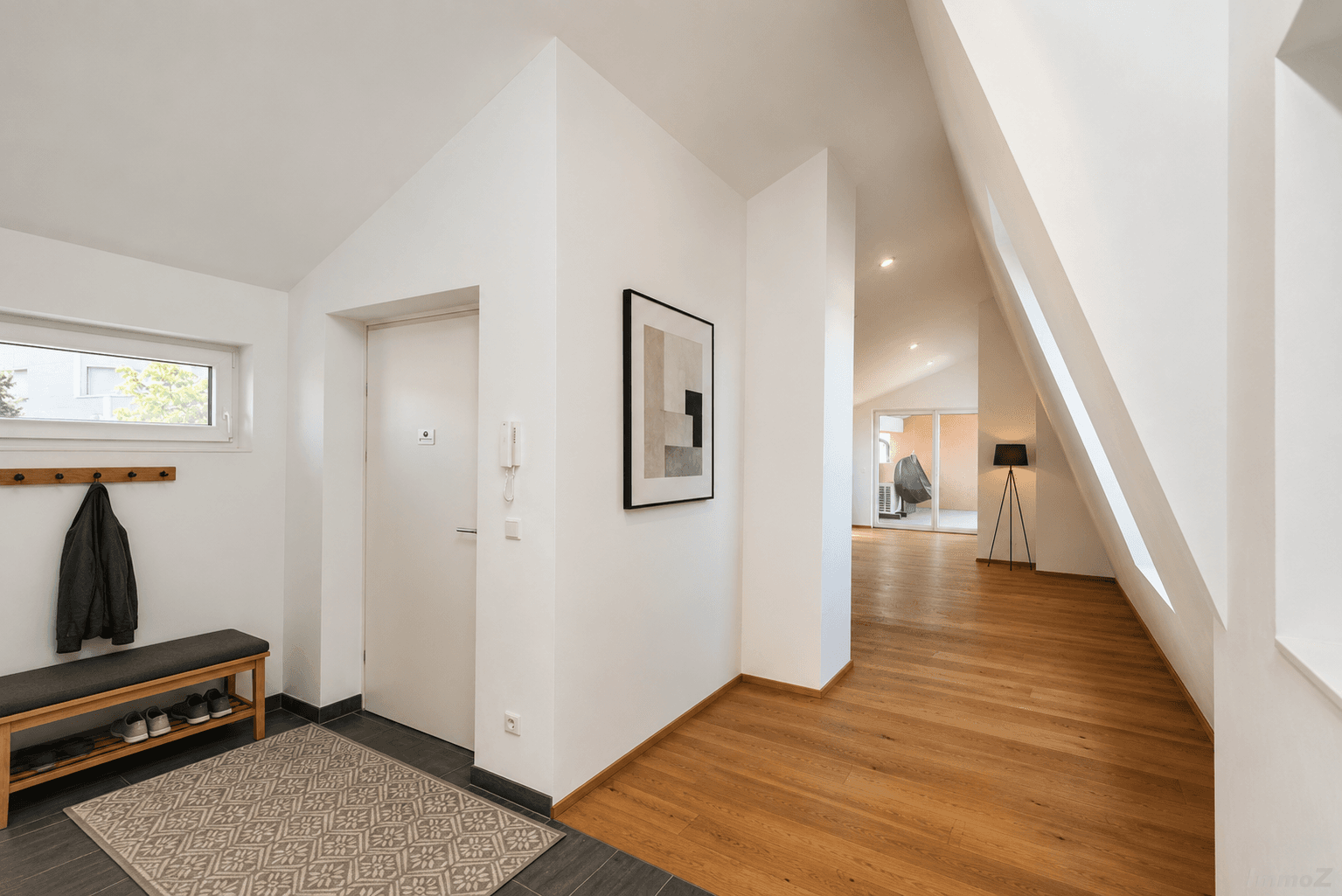 Moderner Eingangsbereich mit Sitzbank, Garderobe, Kunstwerk und offenem Übergang zum Wohnbereich.