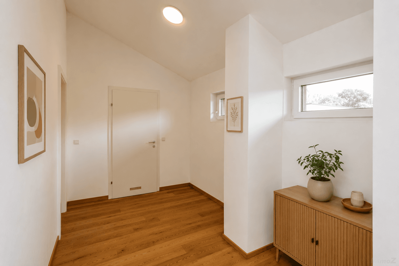 Modern dekorierter Flur mit Holzboden, weißen Wänden und schrägen Decken im Dachgeschoss.