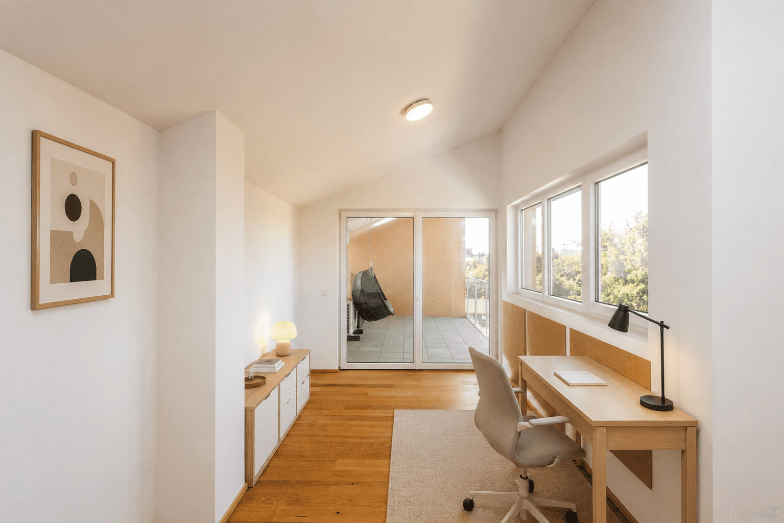 Modernes Arbeitszimmer mit Holzboden, Schreibtisch und direktem Zugang zur Terrasse.