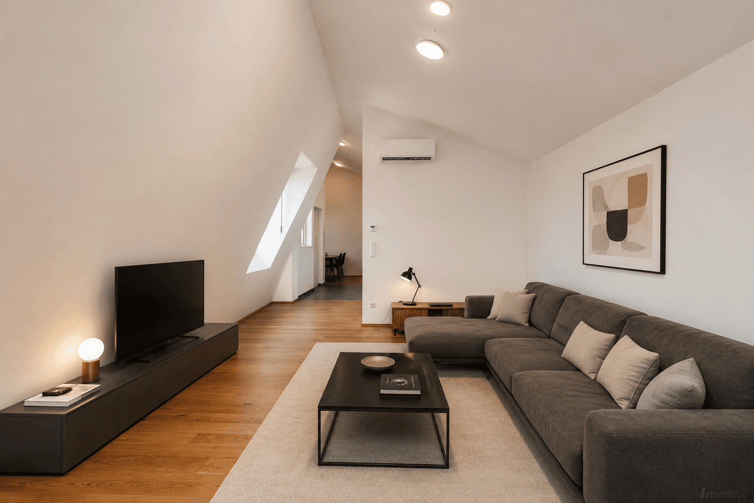Modern eingerichtetes Wohnzimmer mit Sofa, TV-Möbel, Holzboden und Klimaanlage.