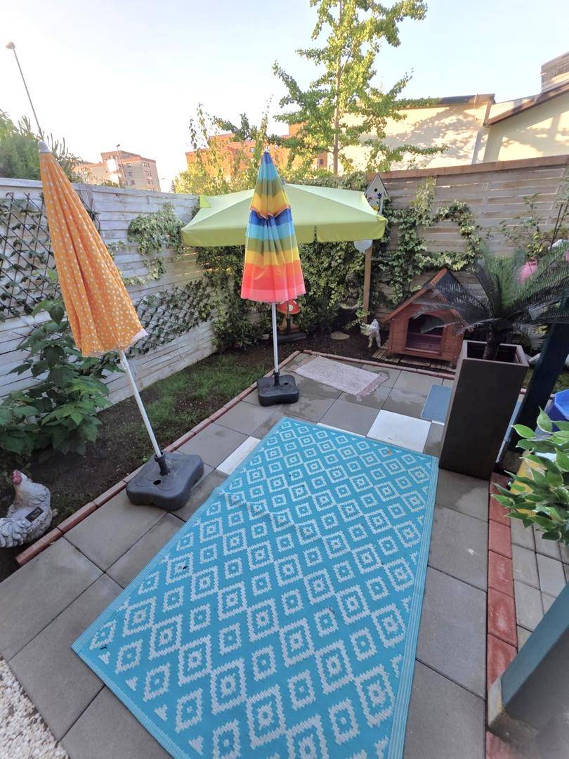 Sonnige Terrasse mit bunten Sonnenschirmen, Teppich und Sitzgelegenheiten.