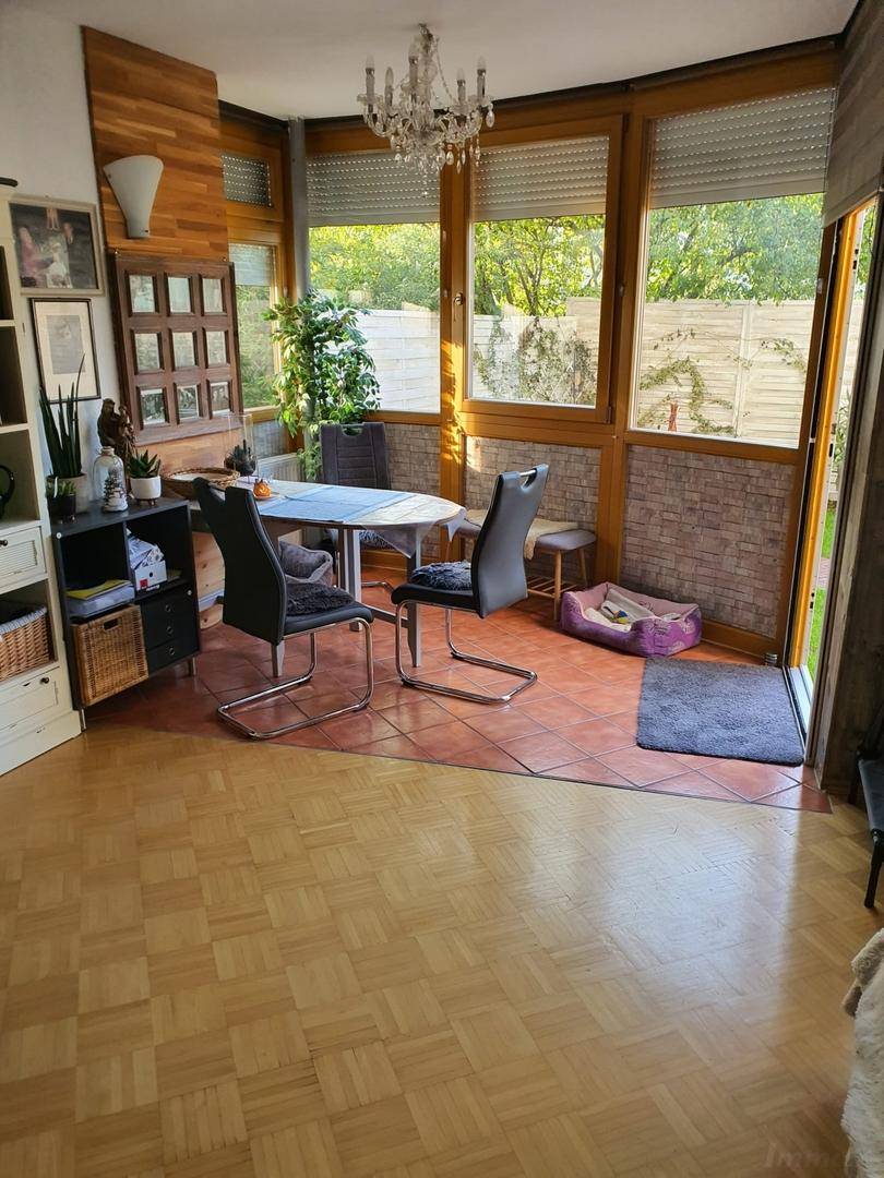 Heller Wohn- und Essbereich mit Parkettboden, großen Fenstern und Zugang zur Terrasse.