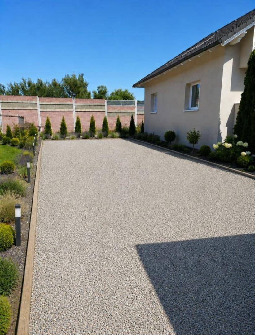 Geräumige Kiesauffahrt vor dem Haus mit gepflegter Bepflanzung und klarem Himmel.