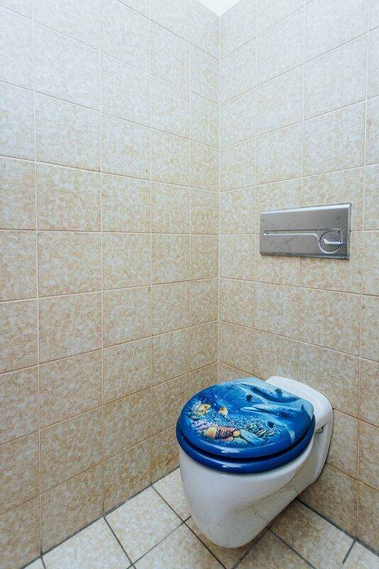Separate Toilette mit beigefarbenen Fliesen und wandhängendem WC.
