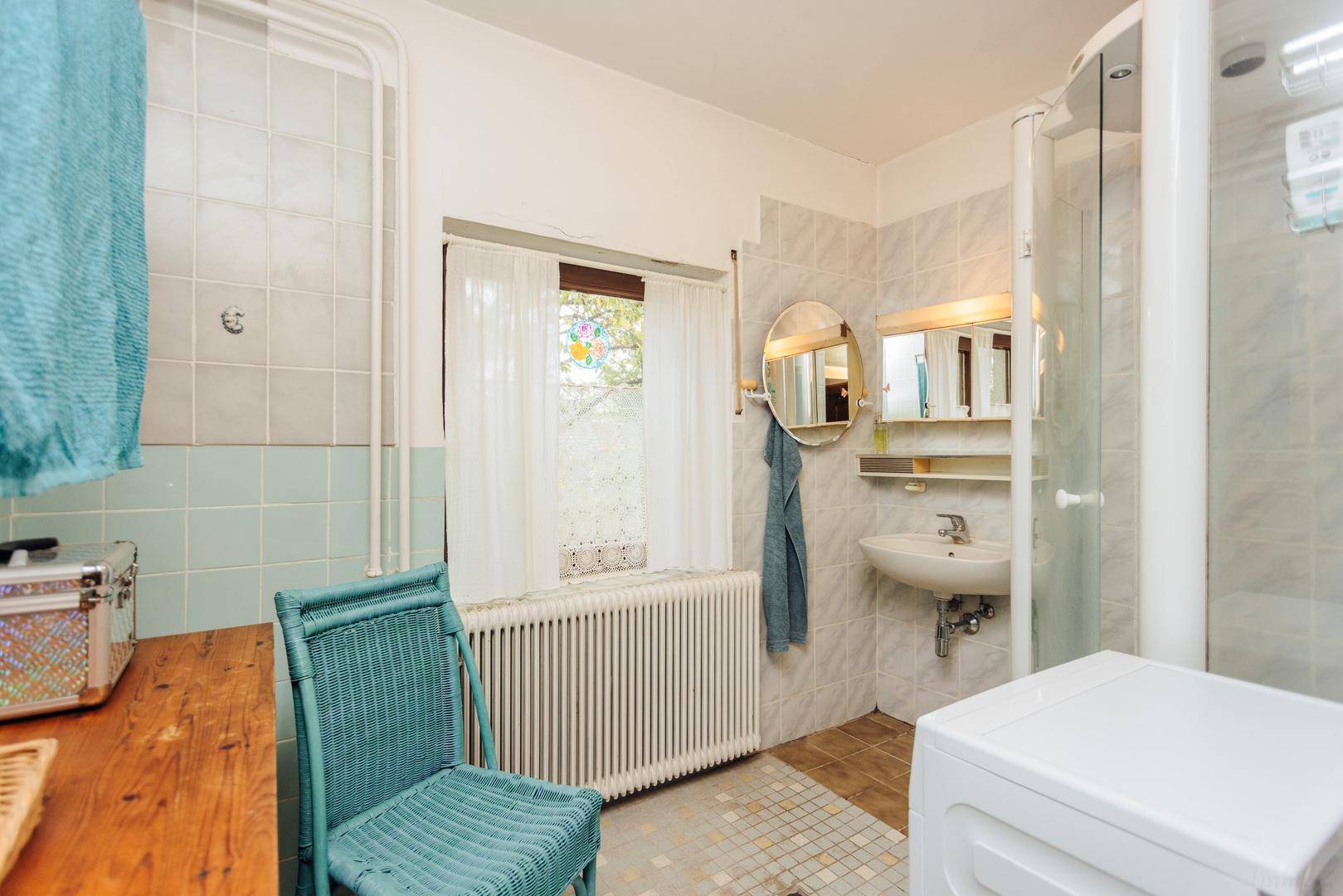 Badezimmer mit Duschkabine, Waschbecken, Waschmaschine und einem Fenster für Tageslicht.