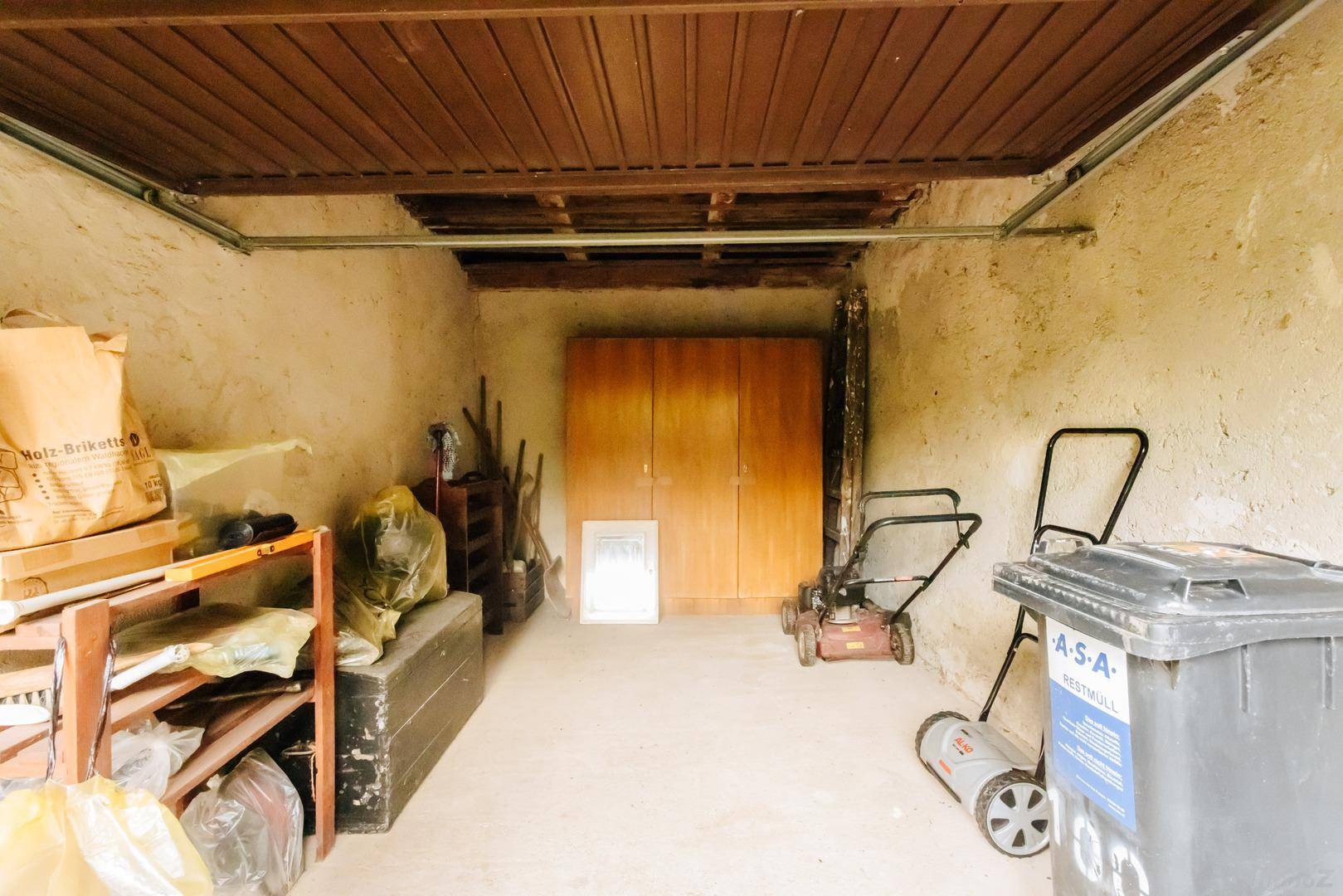 Geräumige Garage oder Abstellraum mit Werkzeugen und Gartengeräten.