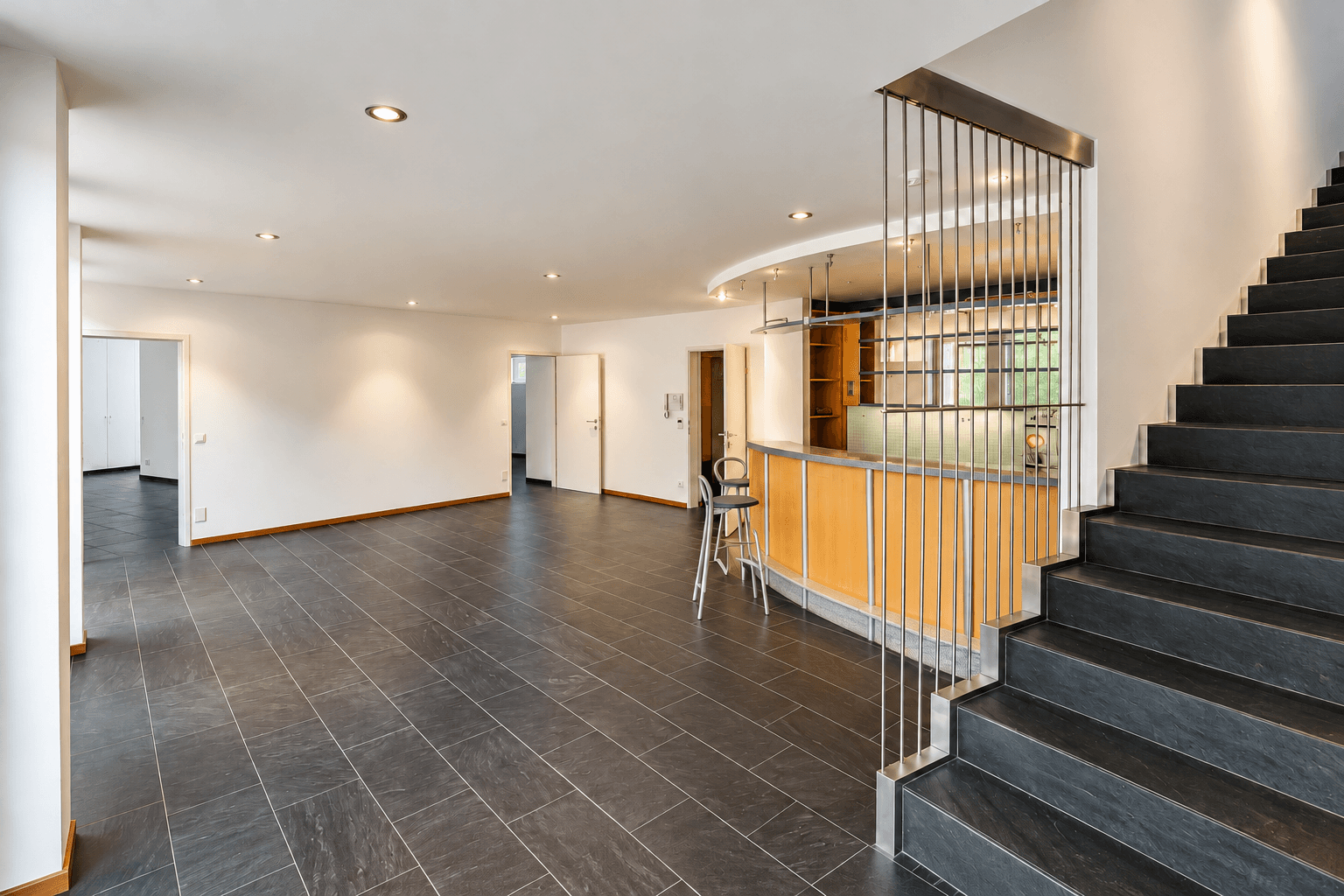Heller minimalistischer Wohnraum mit Bar und Treppe