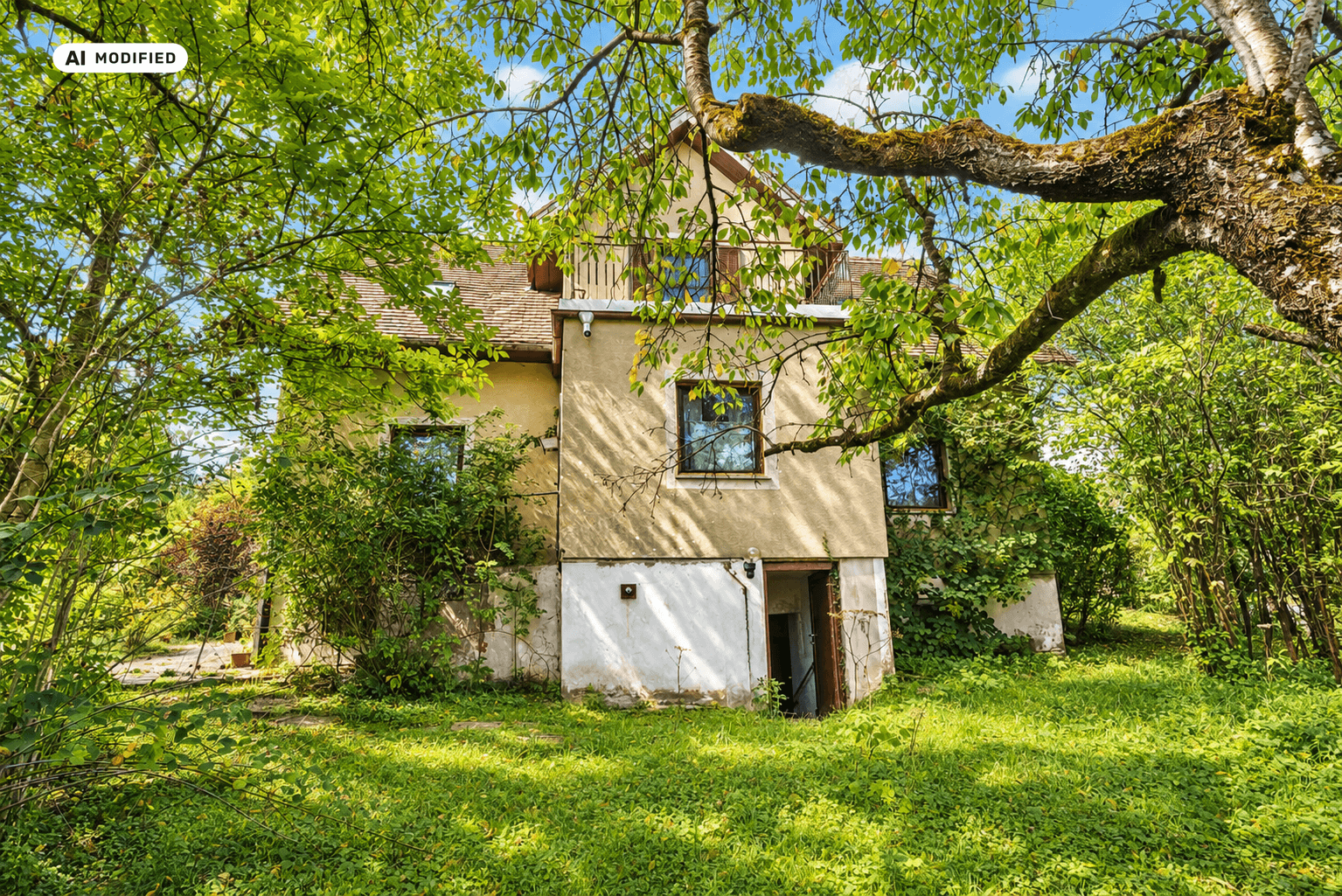 Seitenansicht des Hauses mit älterer Fassade und einem Eingang zum Kellerbereich im Grünen.