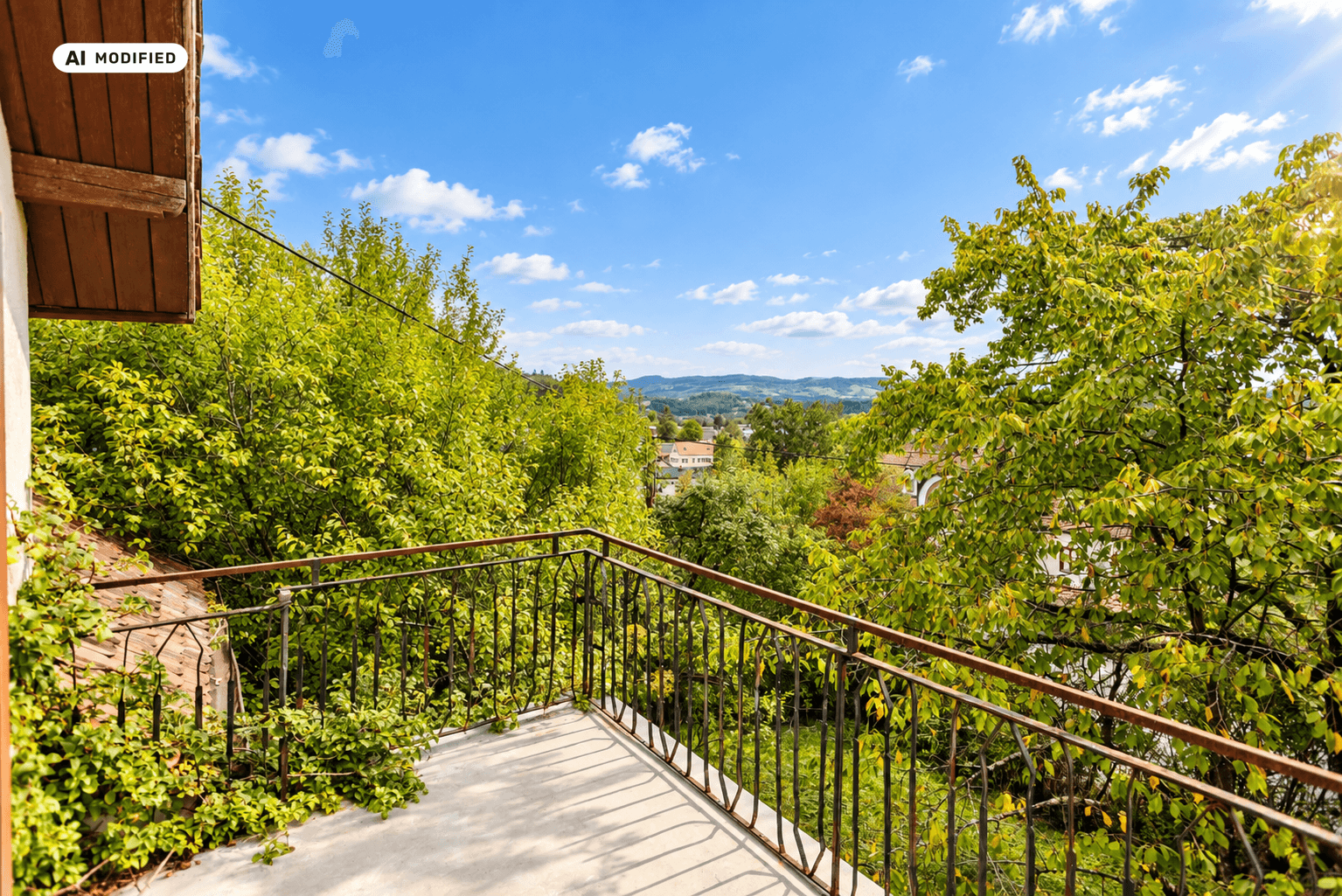Kleiner Balkon mit schmiedeeisernem Geländer und weitem Blick ins Grüne.