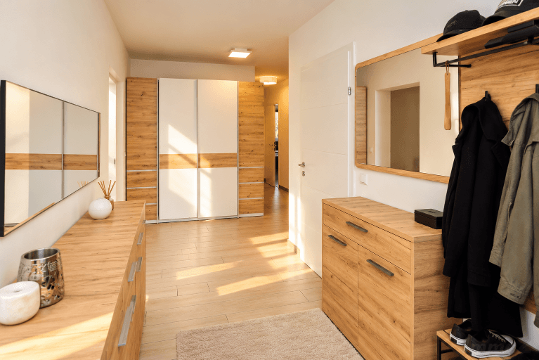 Heller Flur mit Holzoptik-Boden, Einbauschränken und modernem Garderobenbereich.