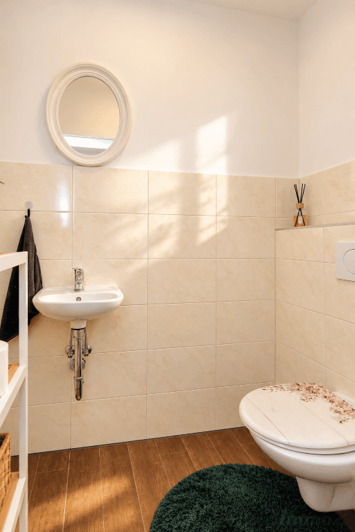 Kleines Gäste-WC mit WC, Handwaschbecken und beigefarbenen Wandfliesen.
