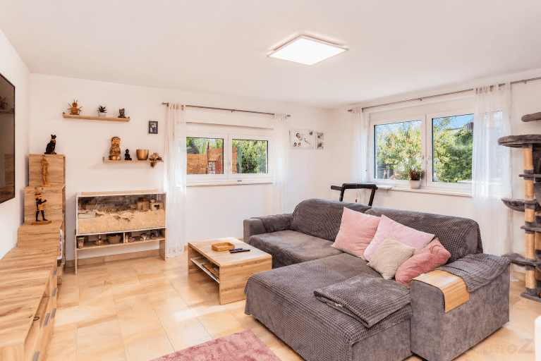 Gemütliches Wohnzimmer mit großem Ecksofa, Fliesenboden und Blick in den Garten.