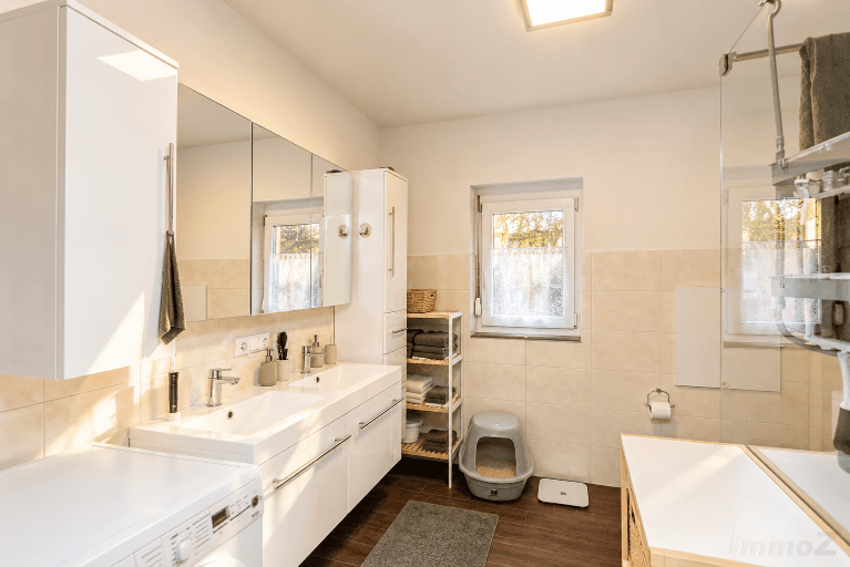 Modernes Badezimmer mit Doppelwaschbecken, Spiegelschrank und Fenster.