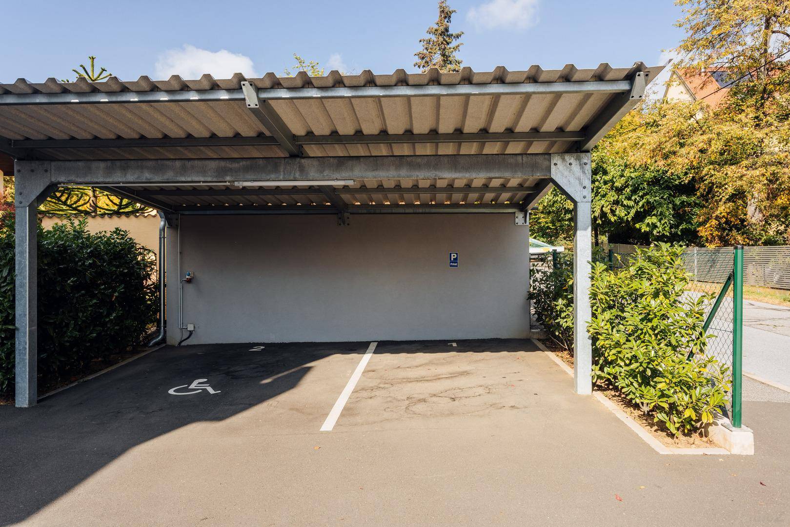 Überdachter Carport mit ausgewiesenem Parkplatz, inklusive barrierefreiem Stellplatz.