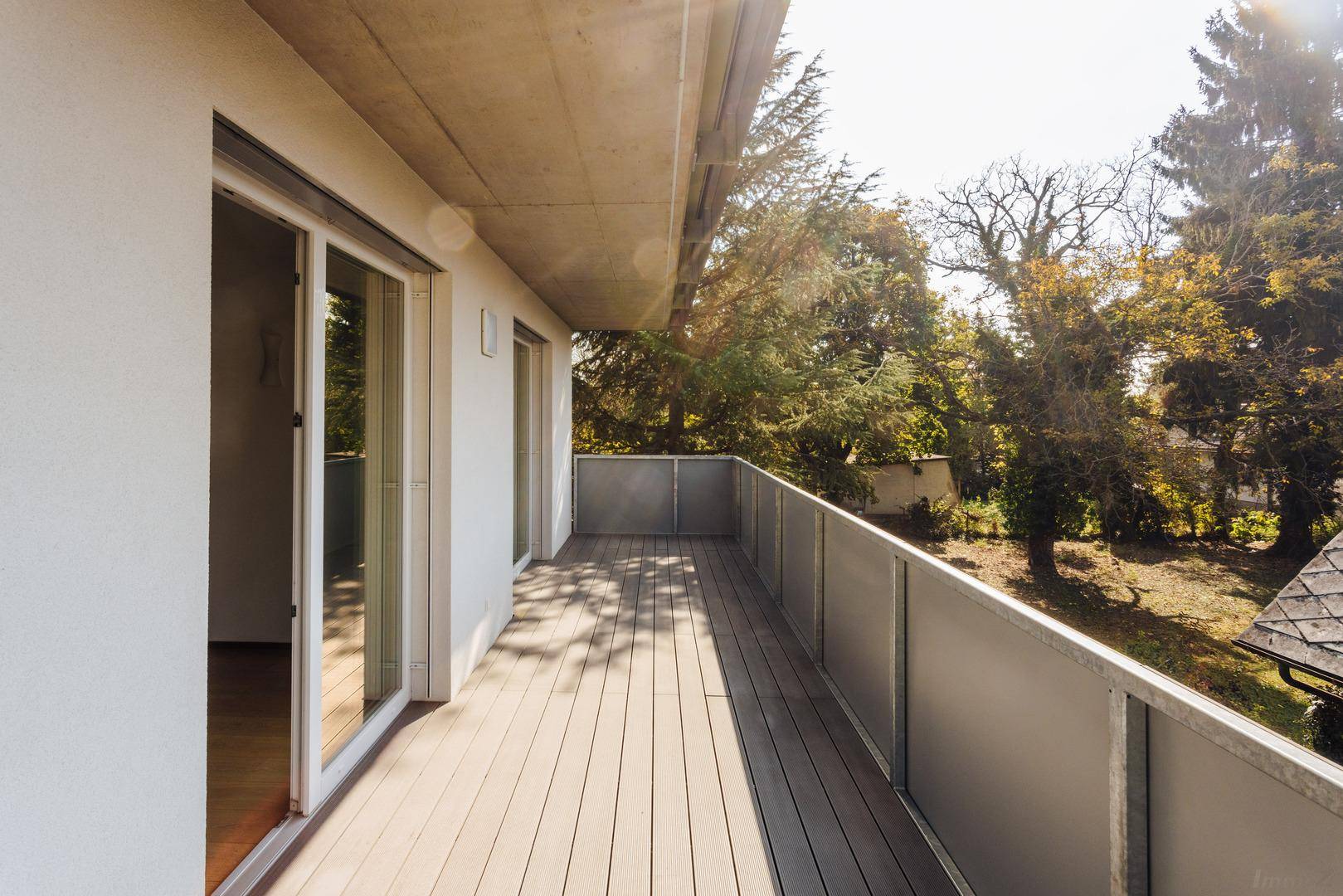 Langer Balkon mit Holzdielen und Metallgeländer, ideal für entspannte Stunden im Freien.