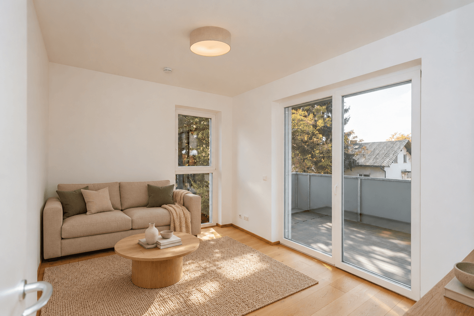 Gemütliches Wohnzimmer mit Sofa, Holzboden und großem Fenster zum Balkon.