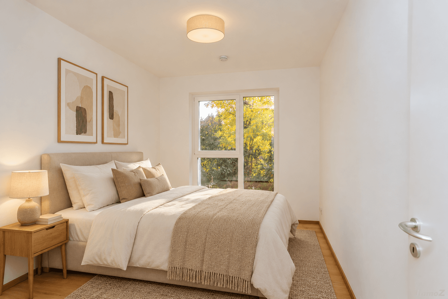 Helles Schlafzimmer mit Doppelbett, Nachttisch und großem Fenster mit Blick ins Grüne.