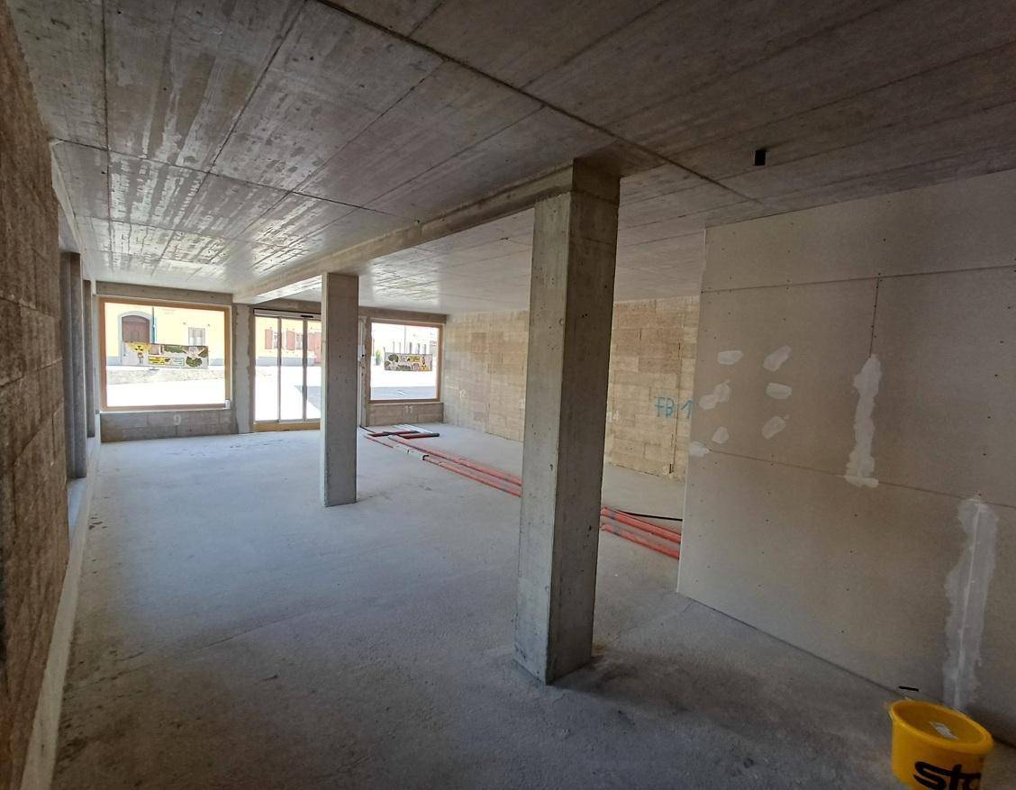 Geräumiger Rohbau mit Betonsäulen, großen Fenstern und vorbereiteten Wänden für den weiteren Ausbau.