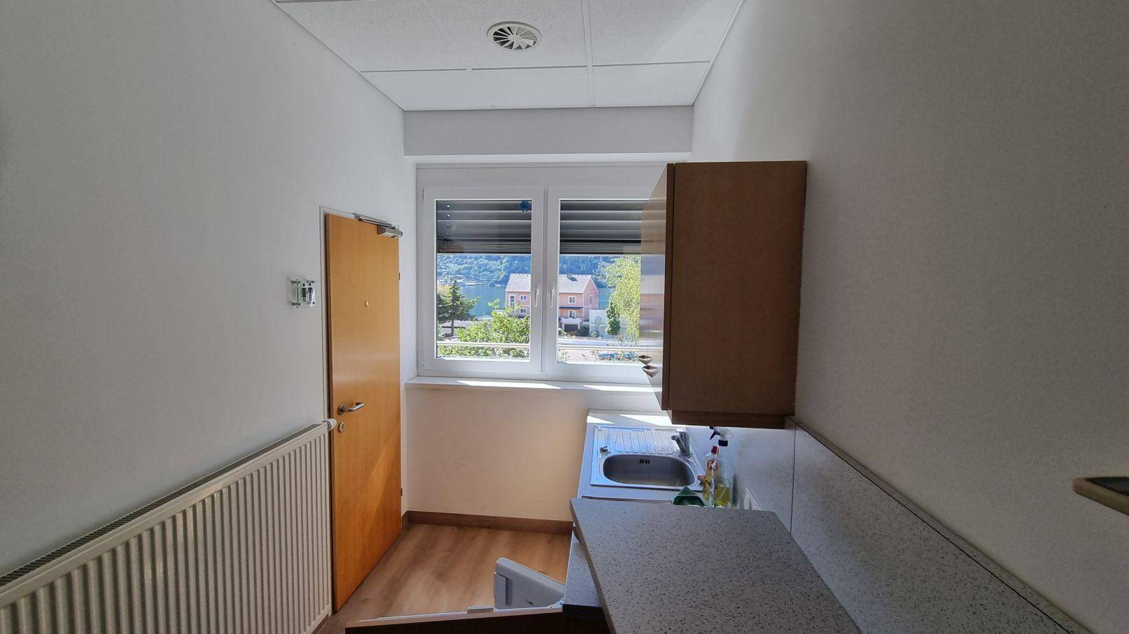 Kleine Küchenzeile mit Spüle, Schrank und Fenster mit Blick auf die umliegende Landschaft.