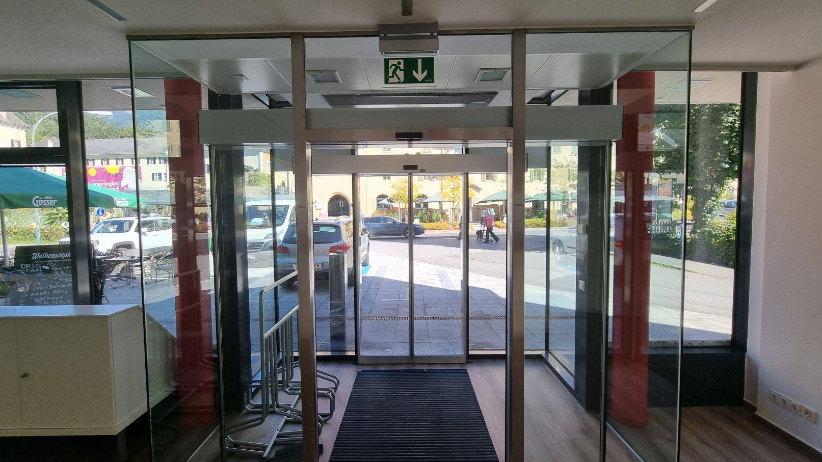 Eingangsbereich mit automatischen Glastüren, die viel Tageslicht hereinlassen und einen Blick nach draußen bieten.