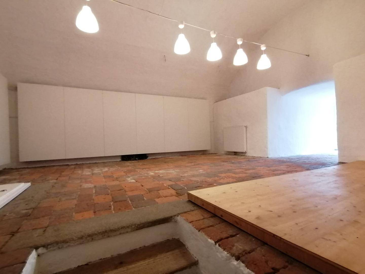 Geräumiger Dachbodenraum mit sichtbaren Ziegelböden und Holzdielen, bietet vielseitige Nutzungsmöglichkeiten.