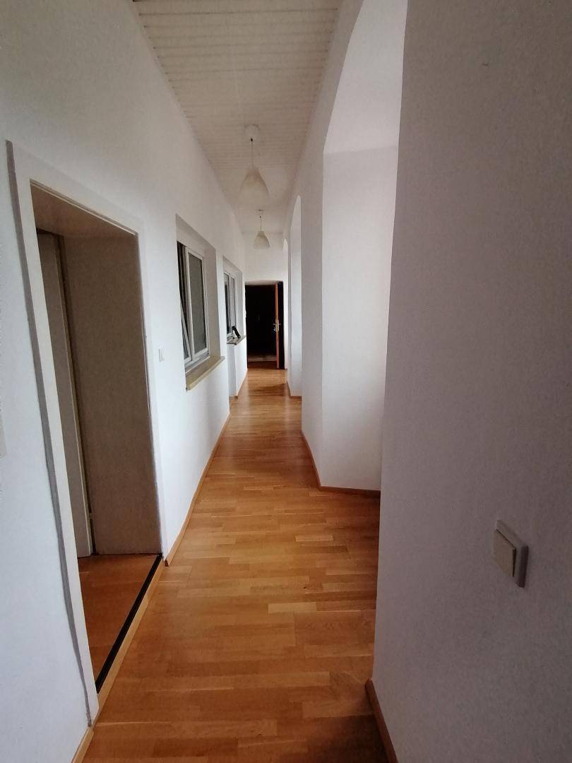 Langer, heller Flur mit Holzdielenboden und mehreren Türen, der zu verschiedenen Räumen führt.