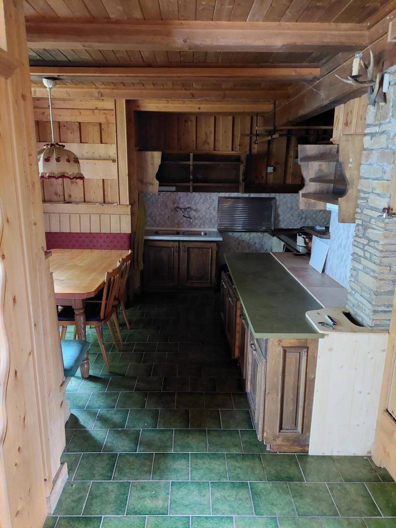 Rustikale Holzküche mit grünen Fliesen, integriertem Essbereich und traditionellem Charme.