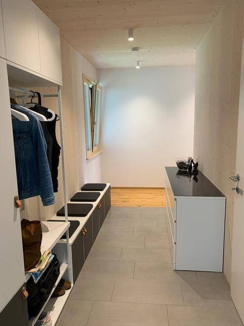 Geräumiger Flur mit moderner Garderobe, Fliesenboden und einem Fenster, das Tageslicht hereinlässt.