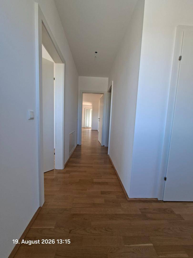 Langer, heller Flur mit Holzparkettboden und Zugang zu mehreren Zimmern.