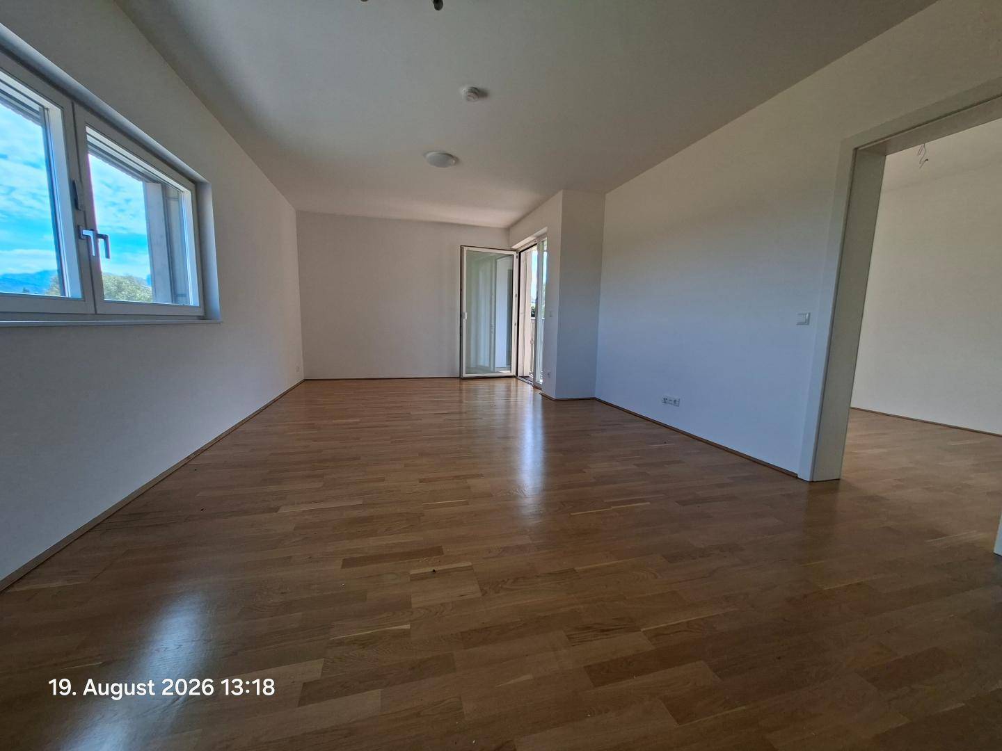 Geräumiger, heller Wohnraum mit Holzparkettboden und großen Fenstern mit Landschaftsblick.